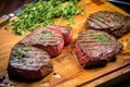 high view of herb rubbed steaks on wooden board