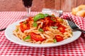 High view of spaghetti pasta with a delicious homemade tomato sauce with homemade basil leaves served on a white plate on a red Royalty Free Stock Photo