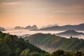 High views with views of mountains and fog interspersed among lush green forests at sunrise, golden light, sky and colorful clouds