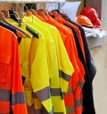 High visibility jackets on a hanger with protective helmets behind, in a work clothes store Royalty Free Stock Photo