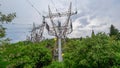 High voltage elecricity pylons come outside a green forest