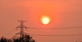 High voltage electric pole and transmission lines at sunset time with orange and red sky and clouds. Architecture. Silhouette Royalty Free Stock Photo