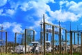 High voltage electric power station - electric poles and lines on very blue cloudy sky background Royalty Free Stock Photo