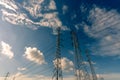 High voltage electric pylon and electrical wire against blue sky and white clouds. Bottom view of Electricity pylon with sunlight Royalty Free Stock Photo