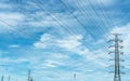 High voltage electric pylon and electrical wire against blue sky and white clouds. Bottom view of Electricity pylon with sunlight Royalty Free Stock Photo