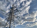 High voltage electric tower against the blue sky. High steel power pole, among the forest. High voltage electrical wires pass Royalty Free Stock Photo