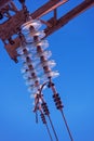 High-voltage electrical insulator made of glass on electric line against the blue sky Royalty Free Stock Photo