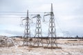 high voltage electrical support. Cloudy sky 3 pillars symmetry distance long in winter cold snowy white. The energy industry. The Royalty Free Stock Photo