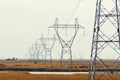 High voltage line with electricity pylons surrounded by cultivated fields. Royalty Free Stock Photo