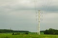 High voltage line with pillars against the background of the forest, field and sky. Royalty Free Stock Photo