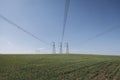 High voltage lines and power pylons in a flat and green agricultural landscape on a sunny day with cirrus clouds in the Royalty Free Stock Photo