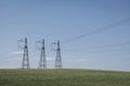 High voltage lines and power pylons in a flat and green agricultural landscape on a sunny day with cirrus clouds in the Royalty Free Stock Photo