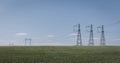 High voltage lines and power pylons in a flat and green agricultural landscape on a sunny day with cirrus clouds in the Royalty Free Stock Photo