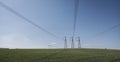 High voltage lines and power pylons in a flat and green agricultural landscape on a sunny day with cirrus clouds in the Royalty Free Stock Photo