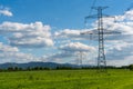 High voltage lines and power pylons in a flat and green agricultural landscape on a sunny day with cirrus clouds in the blue sky Royalty Free Stock Photo