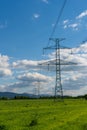 High voltage lines and power pylons in a flat and green agricultural landscape on a sunny day with cirrus clouds in the blue sky Royalty Free Stock Photo