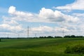 High voltage lines and power pylons in a flat and green agricultural landscape on a sunny day with cirrus clouds in the blue sky Royalty Free Stock Photo