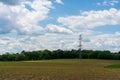 High voltage lines and power pylons in a flat and green agricultural landscape on a sunny day with cirrus clouds in the blue sky Royalty Free Stock Photo