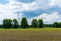 High voltage lines and power pylons in a flat and green agricultural landscape on a sunny day with cirrus clouds in the blue sky Royalty Free Stock Photo