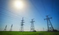 High voltage lines and power pylons in a flat and green agricultural landscape on a sunny day with clouds in the blue sky Royalty Free Stock Photo