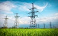 High voltage lines and power pylons in a flat and green agricultural landscape on a sunny day with clouds in the blue sky. Cloudy Royalty Free Stock Photo