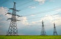 High voltage lines and power pylons in a flat and green agricultural landscape on a sunny day with clouds in the blue sky. Cloudy Royalty Free Stock Photo
