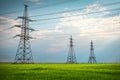 High voltage lines and power pylons in a flat and green agricultural landscape on a sunny day with clouds in the blue sky. Cloudy Royalty Free Stock Photo