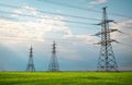 High voltage lines and power pylons in a flat and green agricultural landscape on a sunny day with clouds in the blue sky. Cloudy Royalty Free Stock Photo