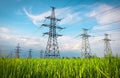 High voltage lines and power pylons in a flat and green agricultural landscape on a sunny day with clouds in the blue sky. Cloudy Royalty Free Stock Photo