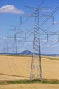 High voltage lines and power pylons in a green agricultural landscape on a sunny day with cirrus clouds in the blue sky. Royalty Free Stock Photo