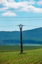 High voltage lines and power pylons in a green landscape on a sunny day with clouds in the blue sky Royalty Free Stock Photo