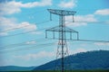 High voltage lines and power pylons in a green landscape on a sunny day with clouds in the blue sky Royalty Free Stock Photo