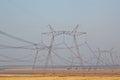 High voltage poles in a row, with a large number of wires are in the desert Royalty Free Stock Photo