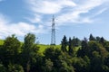 High voltage power line, mountain with green meadow and green trees. Electricity is becoming more and more important, increasing