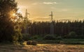 High voltage power line near the bales of straw on a mown wheat field and forest. Royalty Free Stock Photo