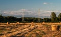 High voltage power line near the bales of straw on a mown wheat field Royalty Free Stock Photo