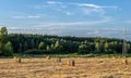 High voltage power line near the bales of straw on a mown wheat field Royalty Free Stock Photo