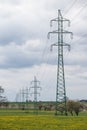 High voltage power lines above spring meadow. Electricity poles Royalty Free Stock Photo