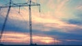 High-voltage power lines against the backdrop of the setting sun in an open area aerovideo