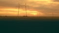 High-voltage power lines against the backdrop of the setting sun on the plain aerovideo