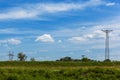 High voltage power lines on blue sky with few white clouds in the field Royalty Free Stock Photo