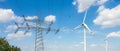 High voltage power lines and electricity transmission tower against blue sky with wind turbine on sunny day Royalty Free Stock Photo