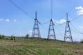 High-voltage power lines in green field against blue sky Royalty Free Stock Photo