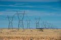 High voltage power lines in mountain desert against blue sky. Royalty Free Stock Photo