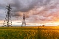 High-voltage power lines passing through a green field, on the background of a beautiful cloudy sky Royalty Free Stock Photo