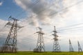 High-voltage power lines passing through a green field, on the background of a beautiful cloudy sky Royalty Free Stock Photo