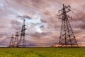 High-voltage power lines passing through a green field, on the background of a beautiful cloudy sky Royalty Free Stock Photo