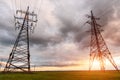 High-voltage power lines passing through a green field, on the background of a beautiful cloudy sky Royalty Free Stock Photo