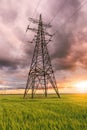 High-voltage power lines passing through a green field, on the background of a beautiful cloudy sky Royalty Free Stock Photo