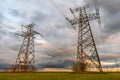 High-voltage power lines passing through a green field, on the background of a beautiful cloudy sky Royalty Free Stock Photo